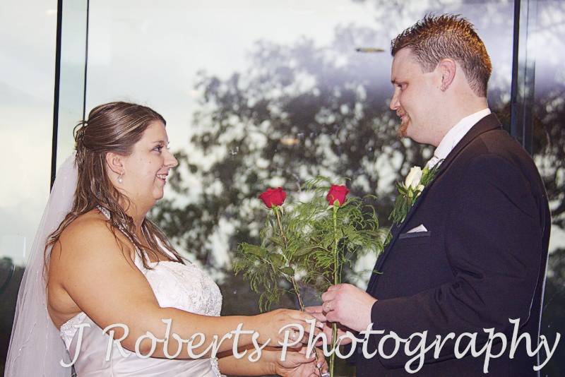 Bride and groom exchanging roses during wedding ceremony - wedding photography sydney